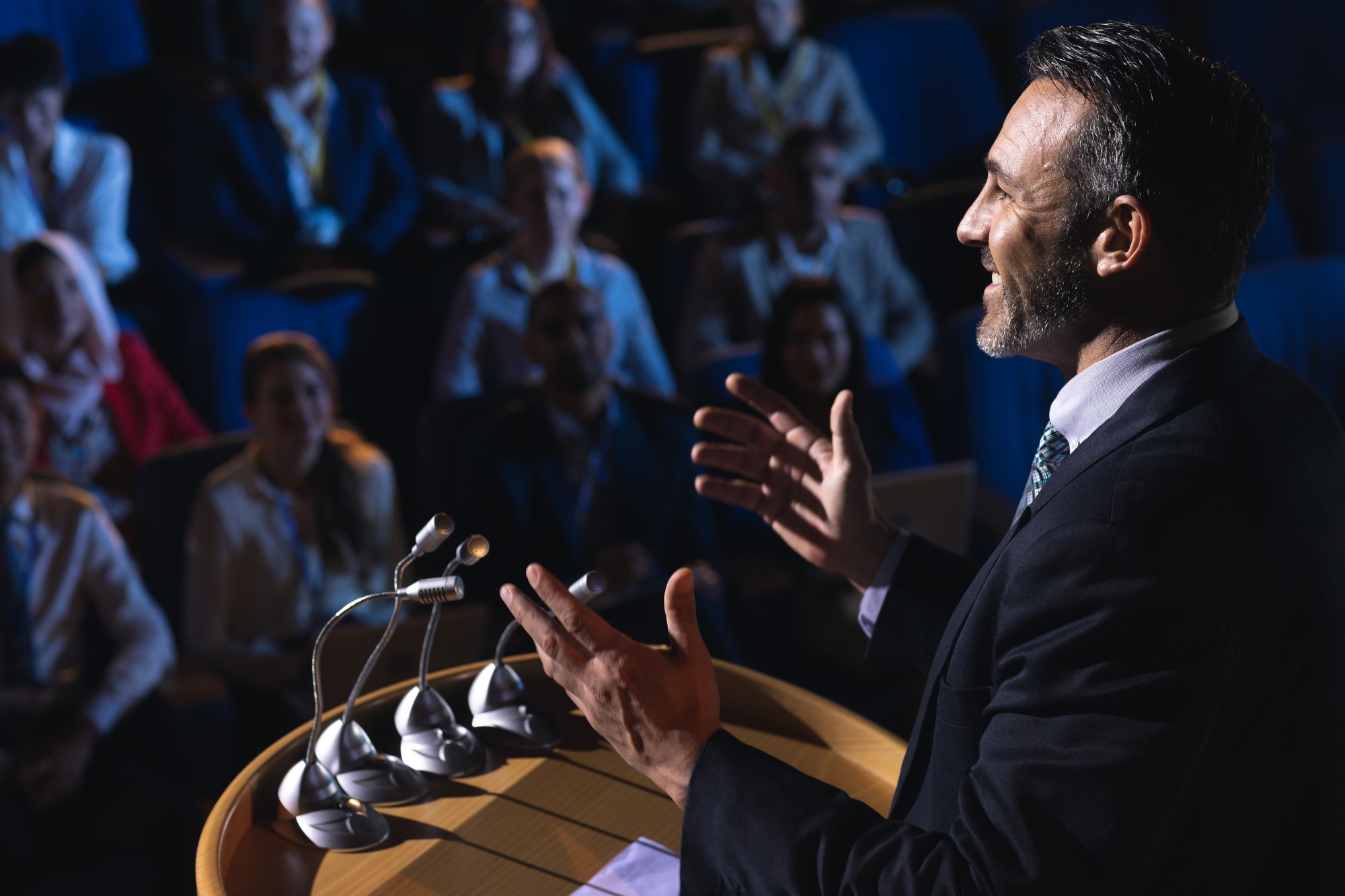 Side view of Caucasian businessman standing and giving presentation in the auditorium